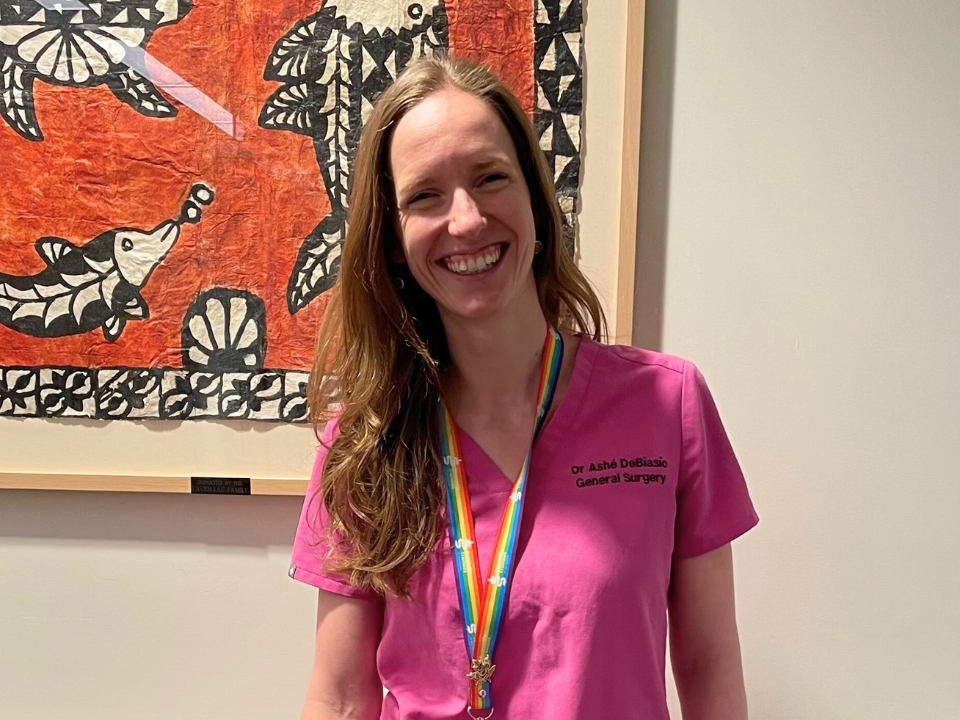 a woman in a pink shirt standing in front of a painting