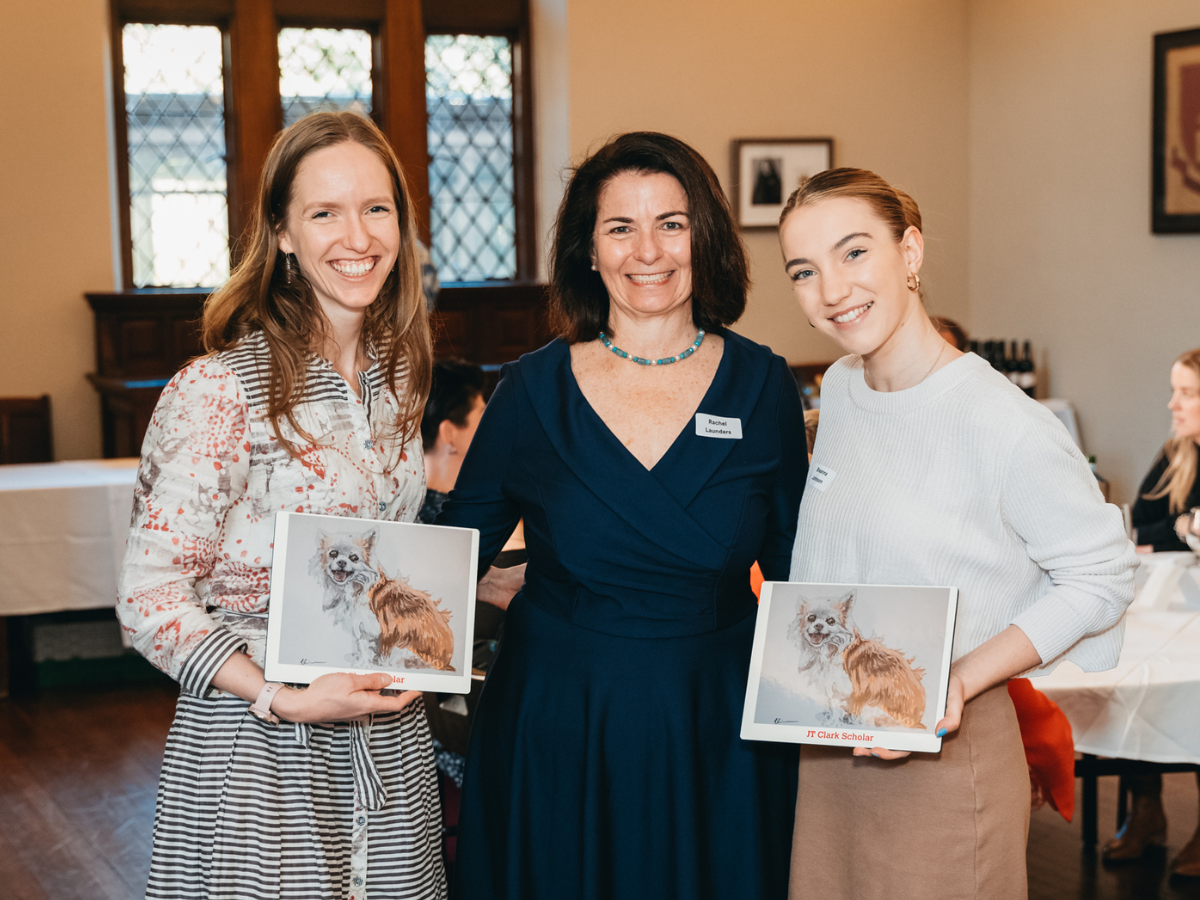 three women holding up framed pictures of a dog at a Sancta event