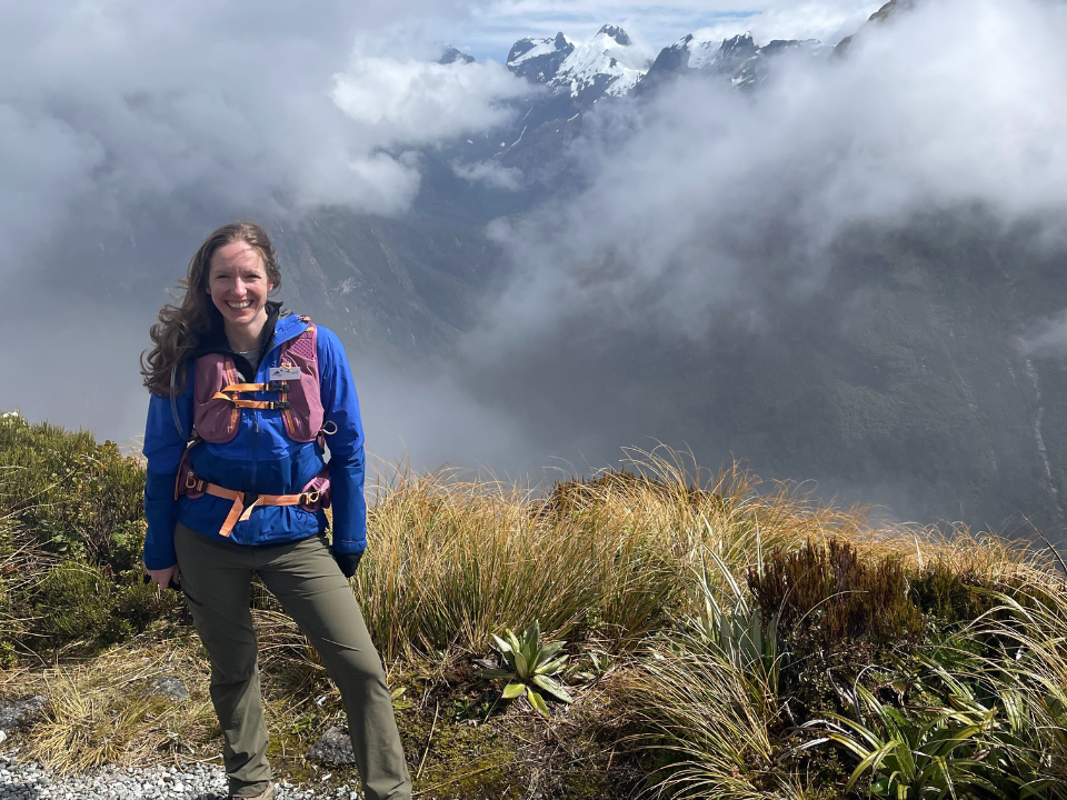 a woman standing on top of a mountain with clouds